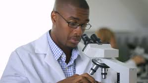 African American male looking into microscope
